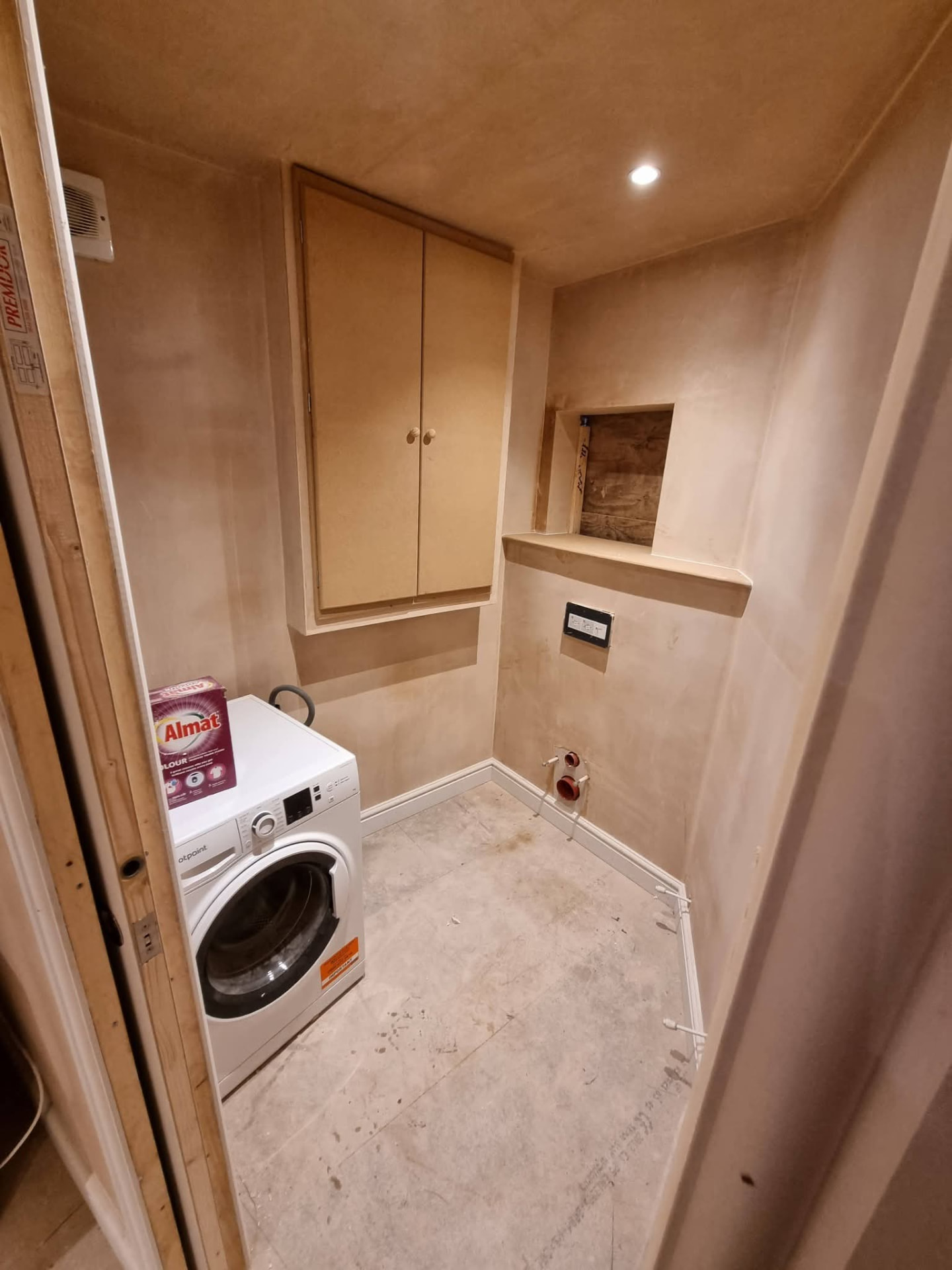 Plastered utility and WC area with washing machine, boiler cupboard and exposed toilet connections