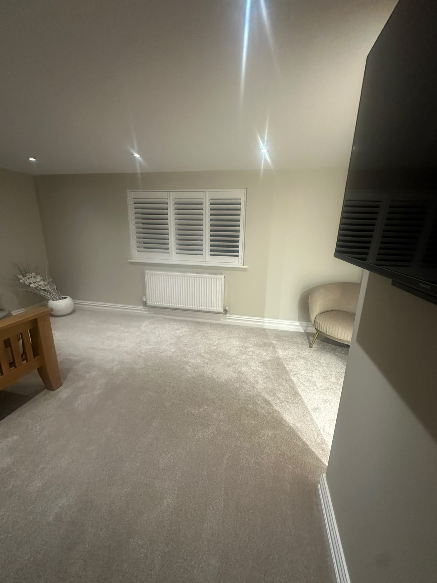 Finished loft bedroom with shuttered window, radiator and carpeted floor