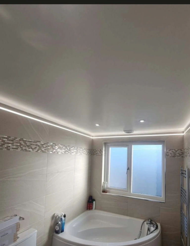 Finished bathroom at the Prestwich project with corner bath, window, towel radiator and perimeter ceiling lighting