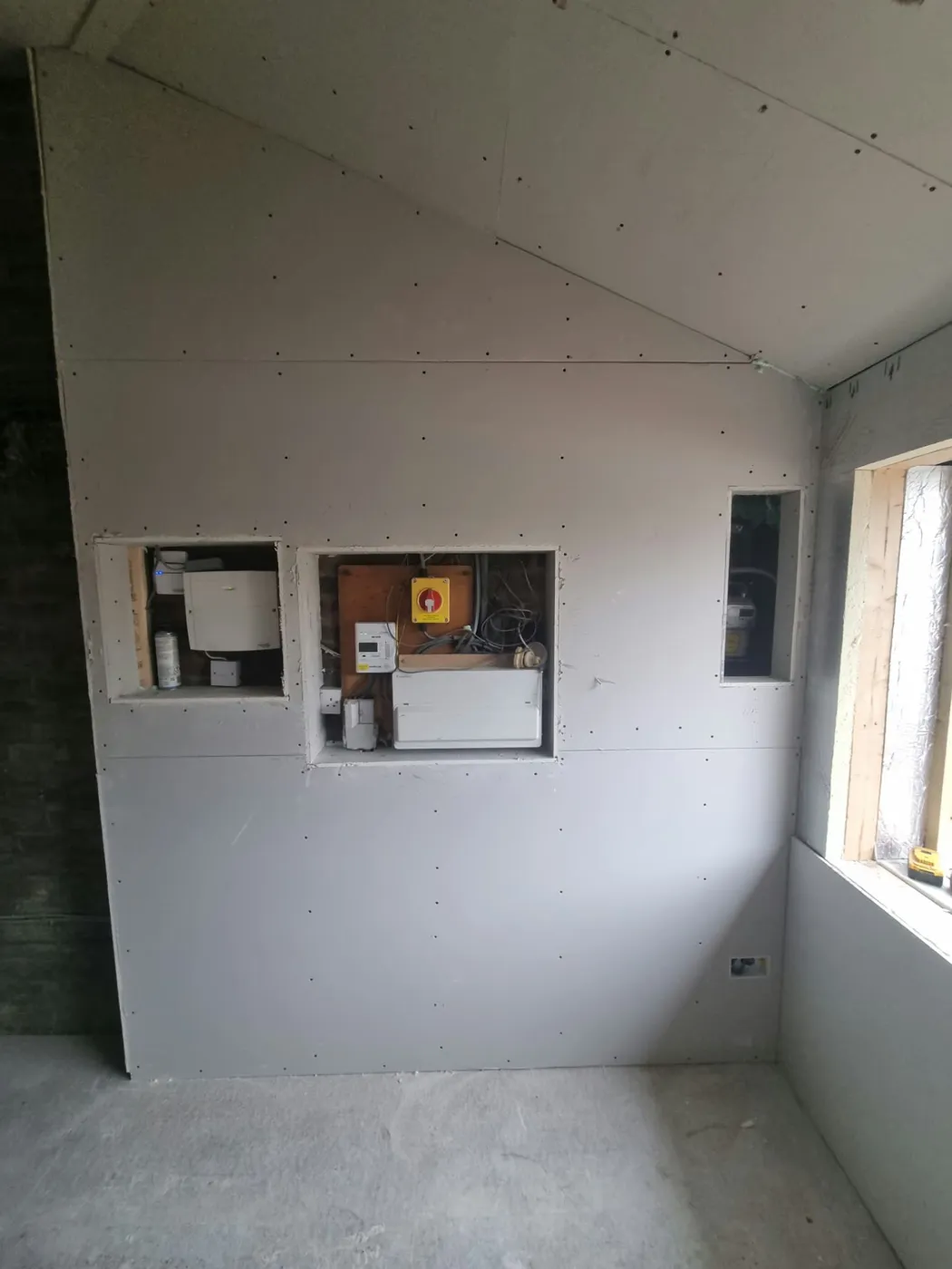 Plasterboarded wall in the Marple conversion with neat openings for the meters and consumer unit