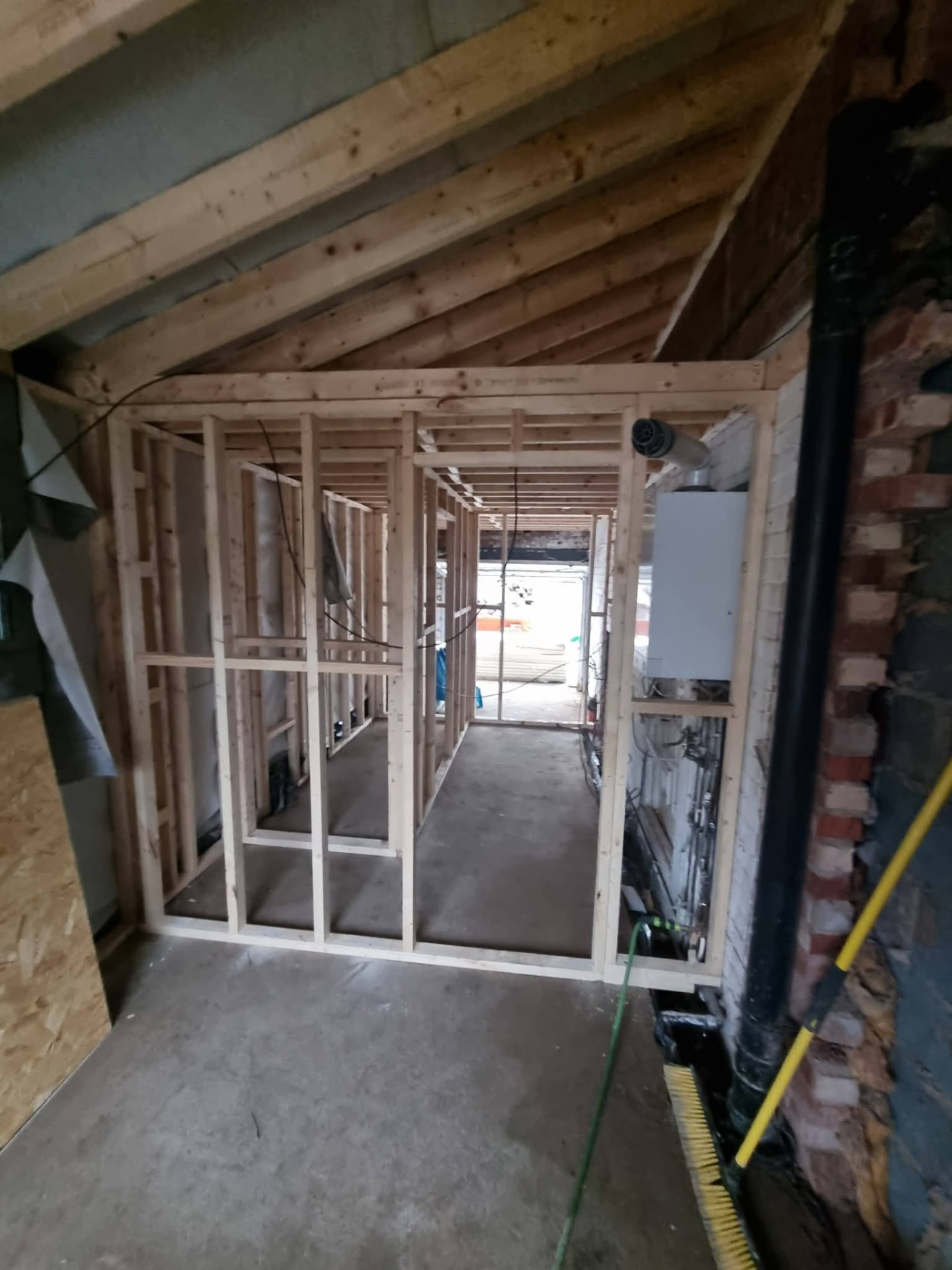 Timber-framed internal rooms beneath pitched roof timbers with exposed boiler and pipework