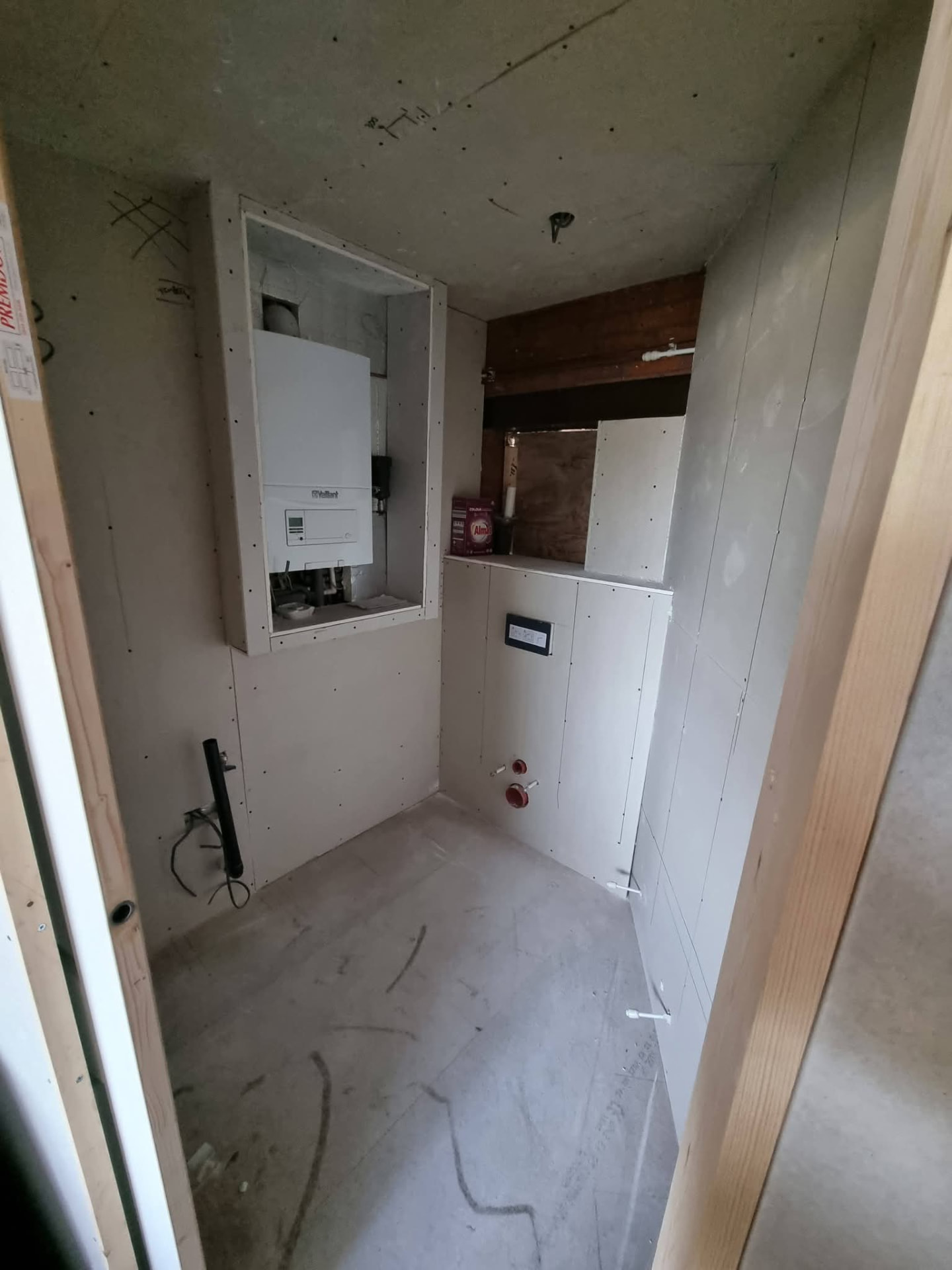 Plasterboard-lined WC area with boxed-in boiler and toilet connections before fitting