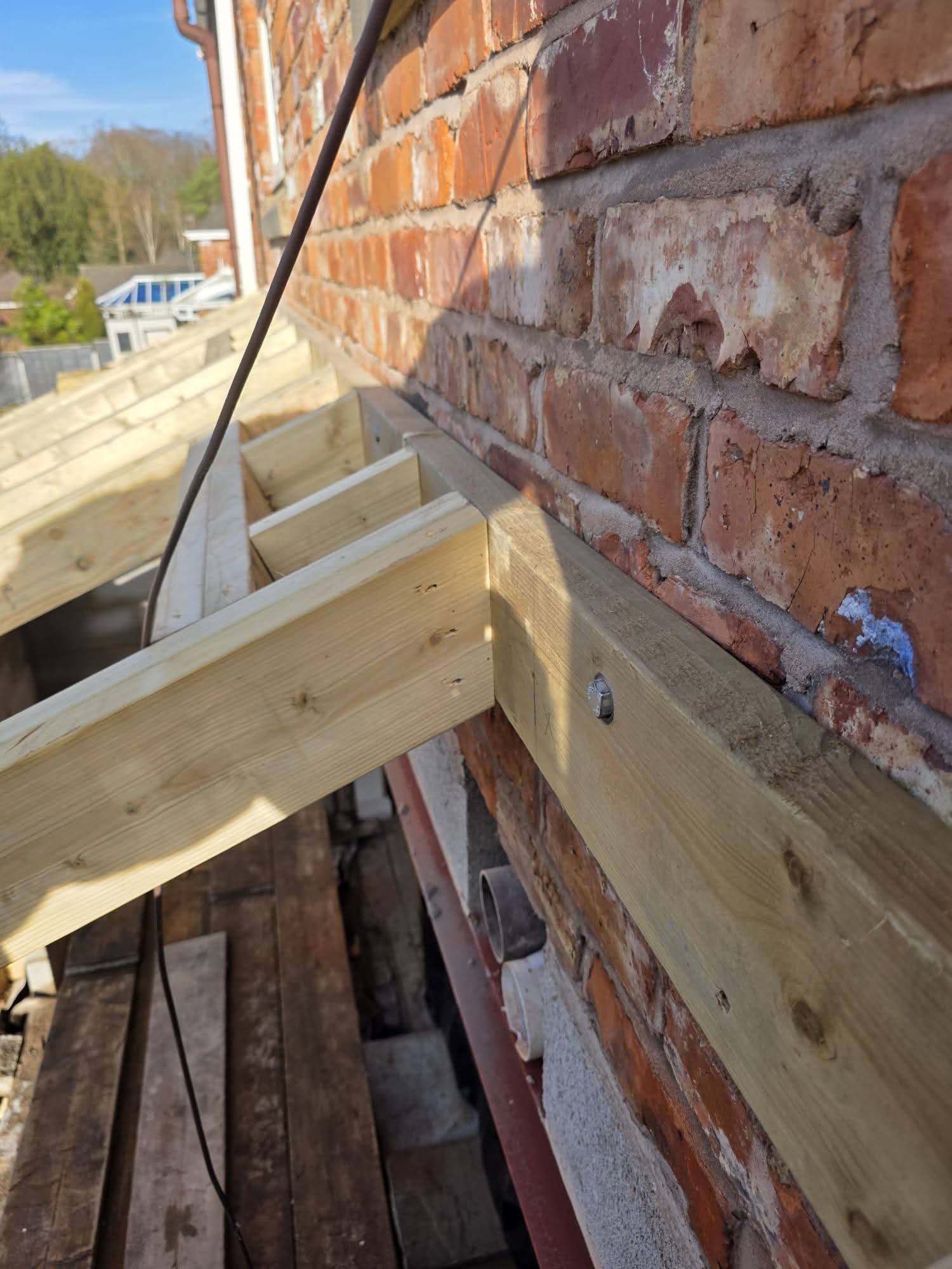 Bolted timber wall plate and rafters against the existing brick house