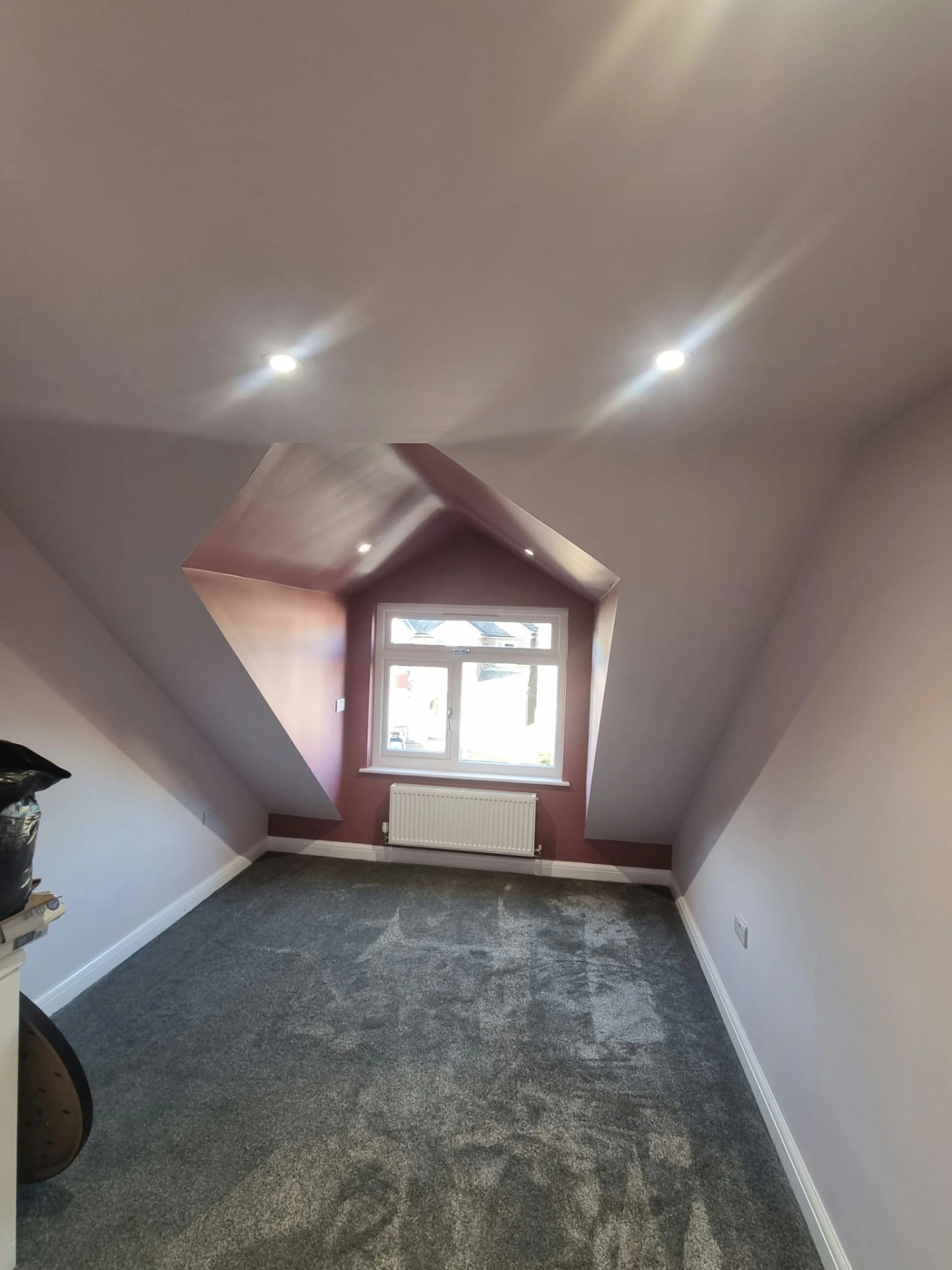Finished carpeted room in Prestwich with sloping ceilings, a dormer window and radiator
