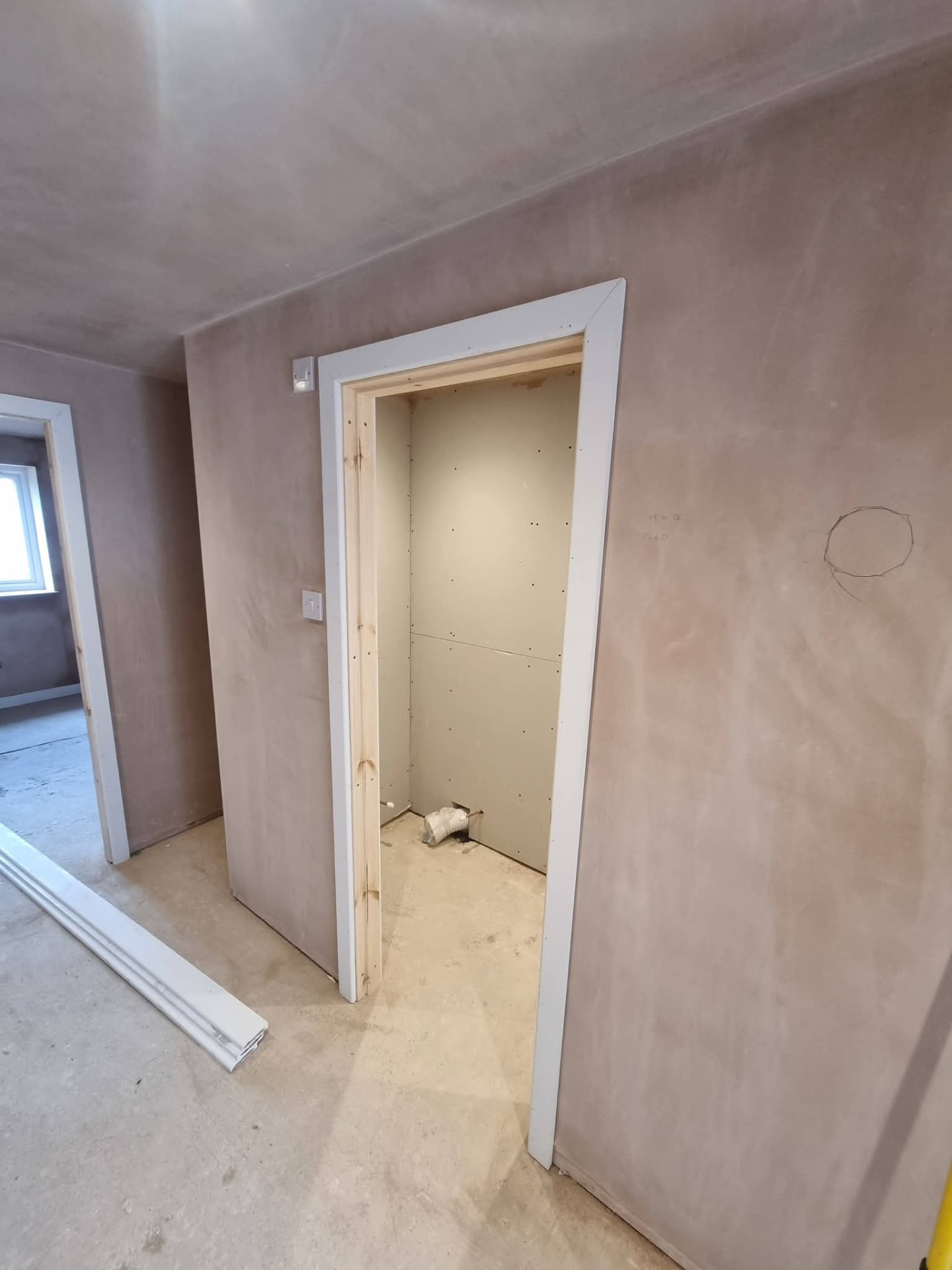 Plastered hallway with a doorway into a plasterboard-lined room and exposed plumbing