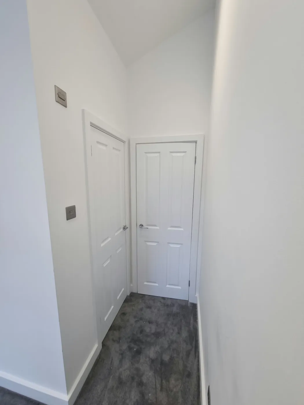 Plastered and decorated hallway with white panelled doors and grey carpet in the Marple conversion