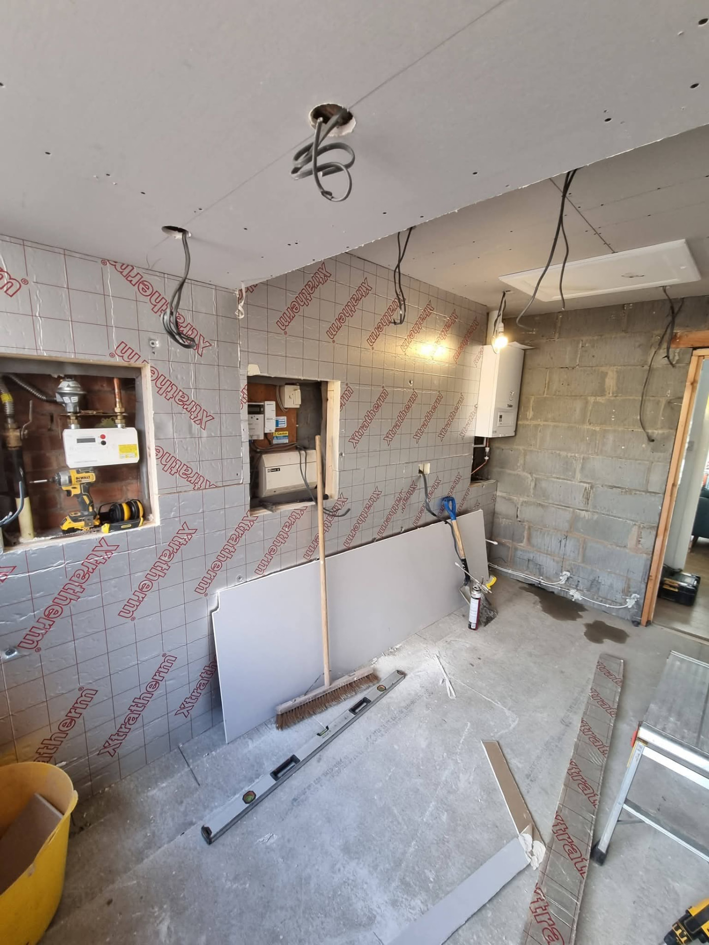 Insulated garage interior with plasterboard ceiling, exposed wiring and service openings