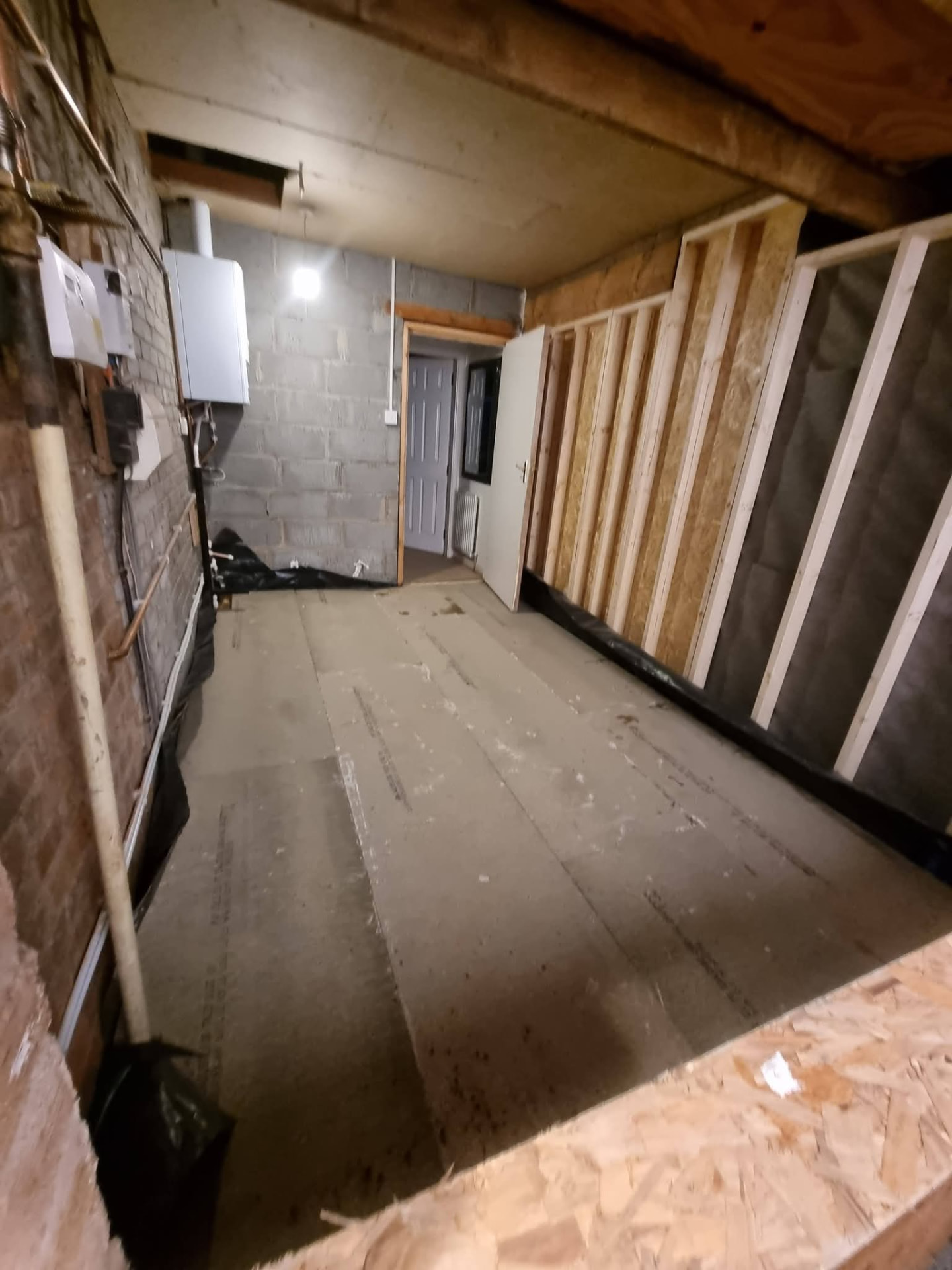 Garage interior with boarded floor, timber wall framing and existing doorway
