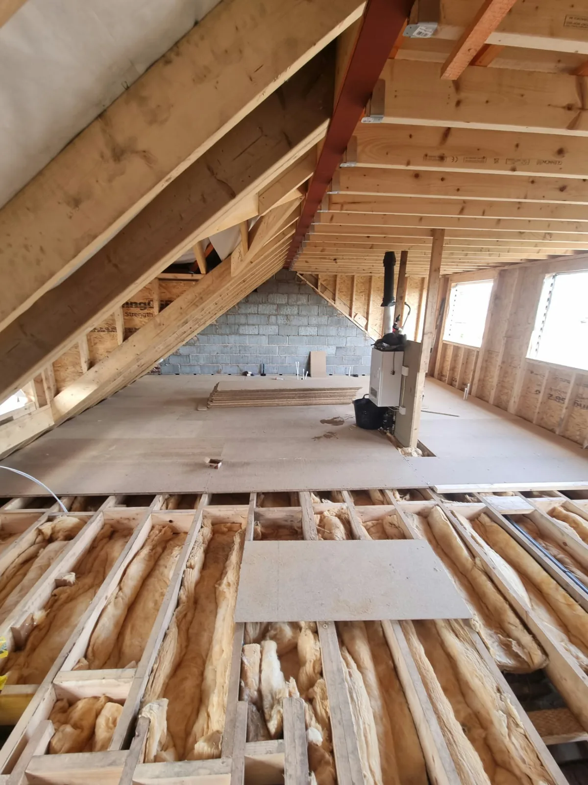 Prestwich loft during construction showing a steel beam, new floor joists with insulation and timber-framed walls