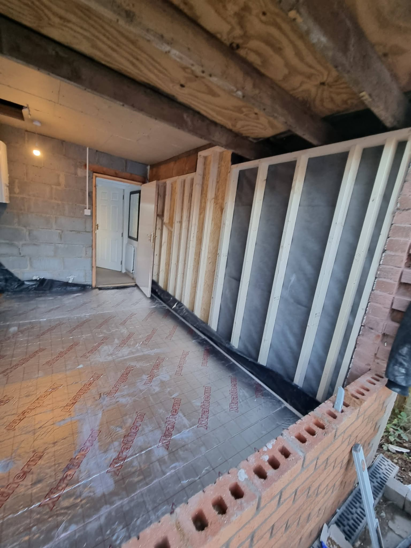 Garage interior with timber wall framing, exposed roof timbers and foil-faced floor insulation