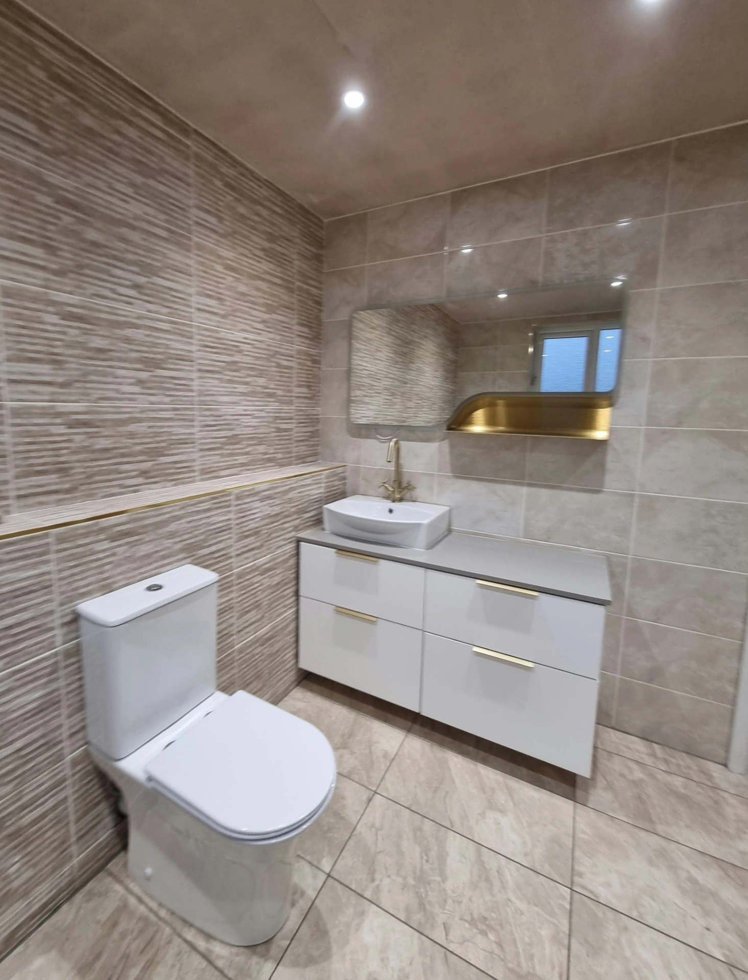 Bathroom vanity, rectangular basin, wall mirror and toilet with gold-coloured fittings at the Prestwich project