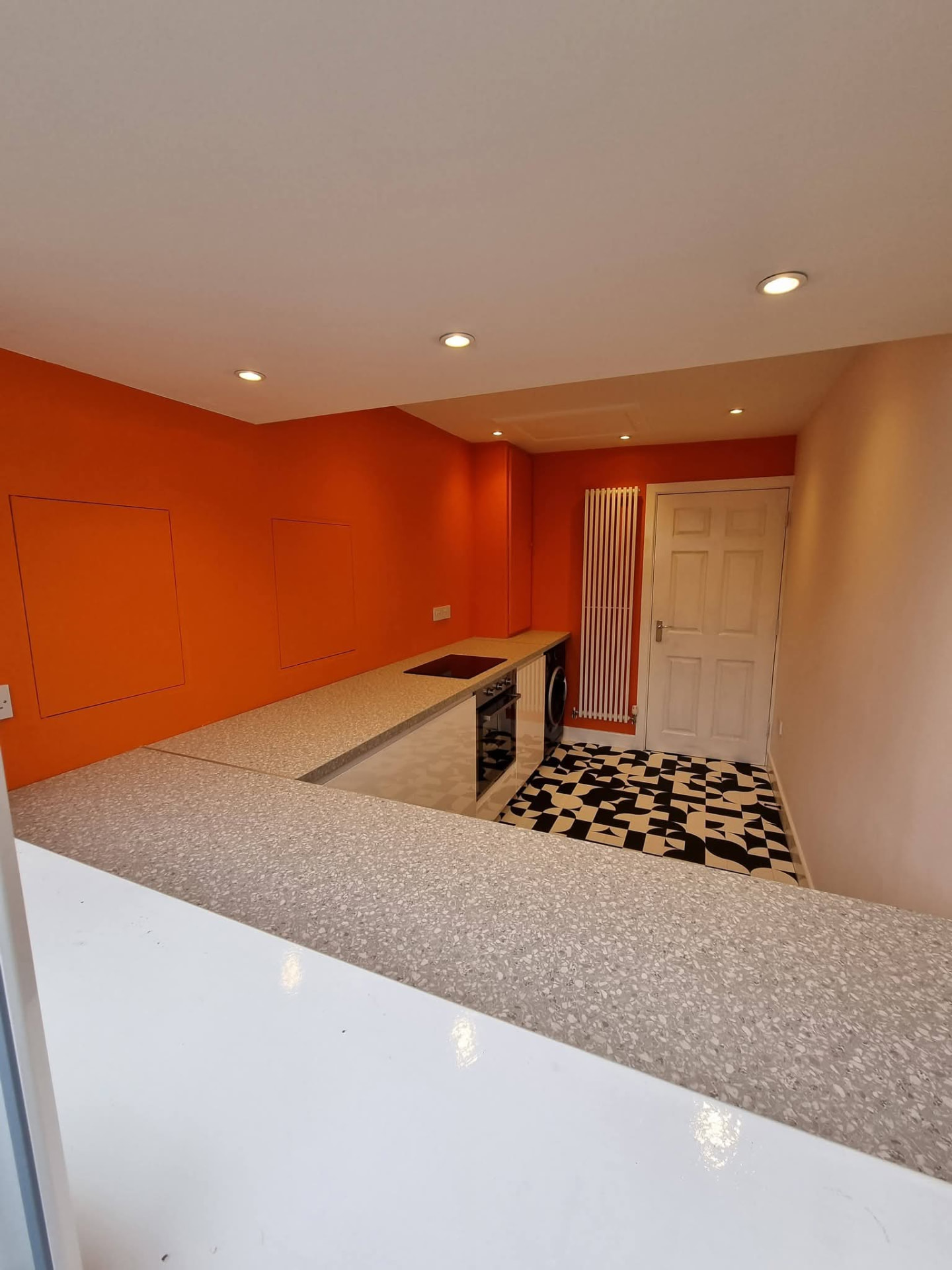 Finished kitchen with orange walls, white cabinets, oven and patterned floor