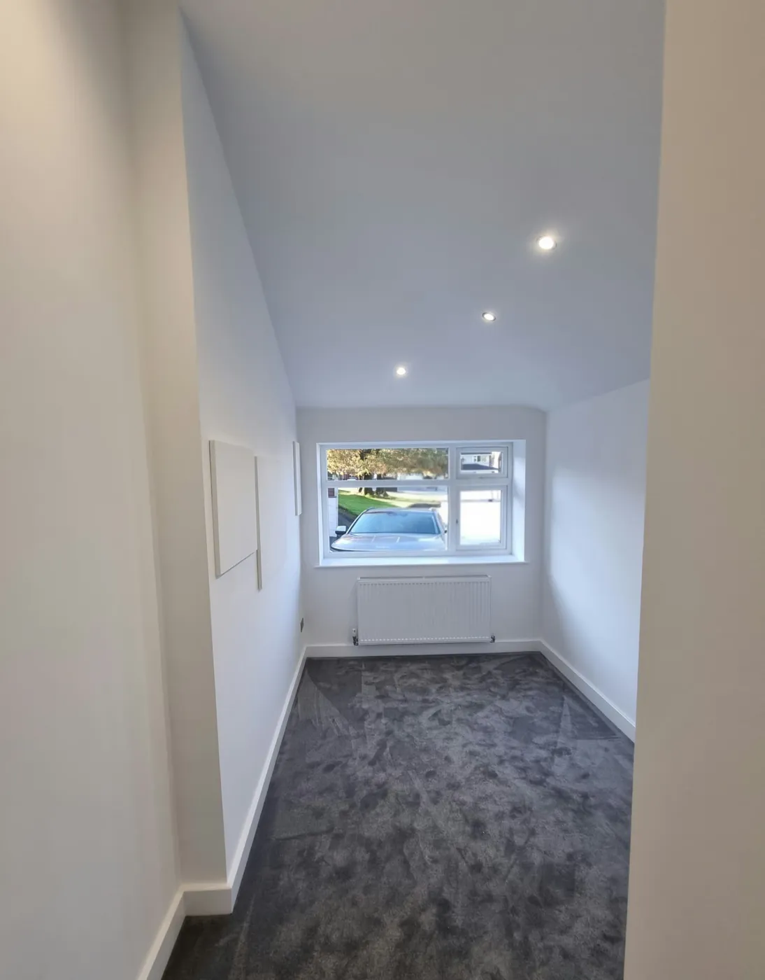 Finished carpeted family playroom in Marple with white walls, recessed ceiling lights and front window
