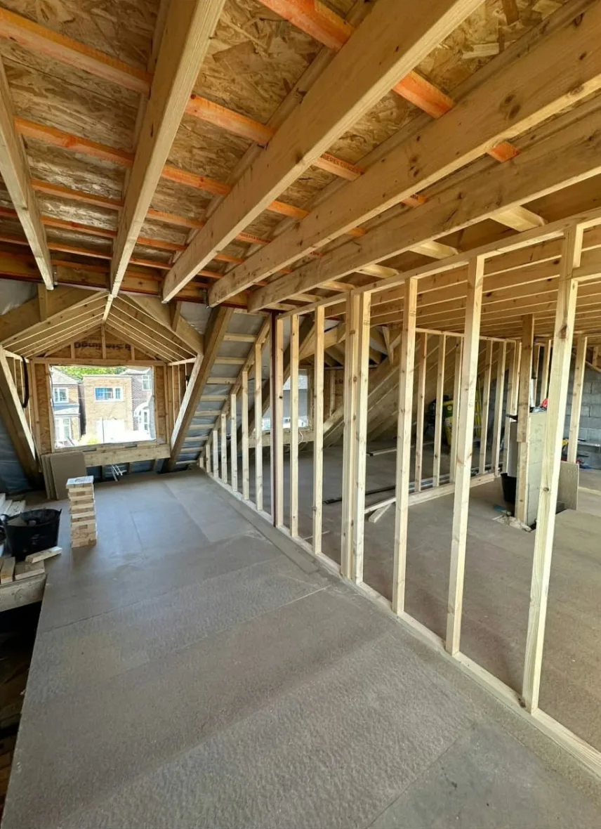 Prestwich loft during construction with exposed roof timbers, stud partition walls and a dormer window opening