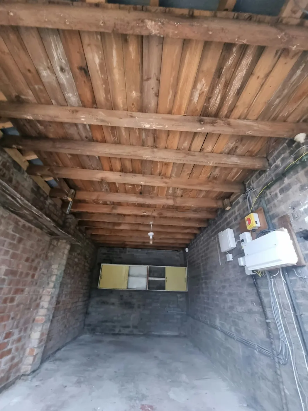 Before: Original Marple garage with exposed brick walls, timber ceiling and bare concrete floor