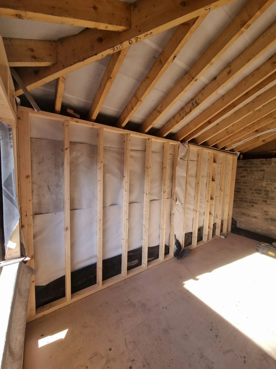 New timber stud framing lining the garage walls beneath the pitched roof timbers
