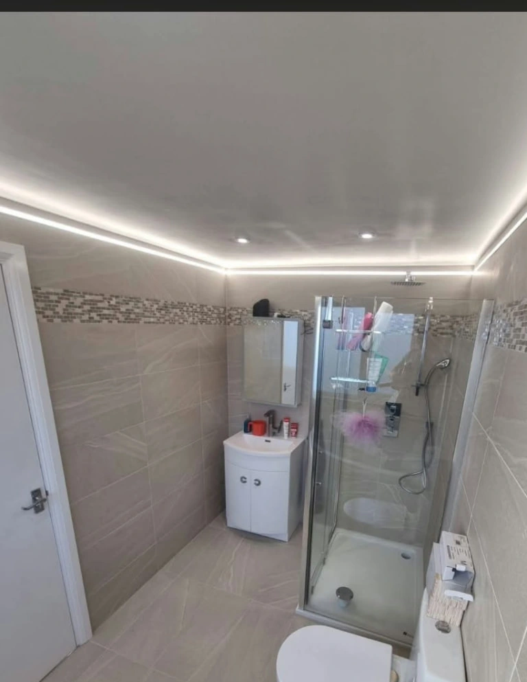 Another view of a tiled bathroom at the Prestwich project showing shower enclosure, basin, toilet and ceiling lighting