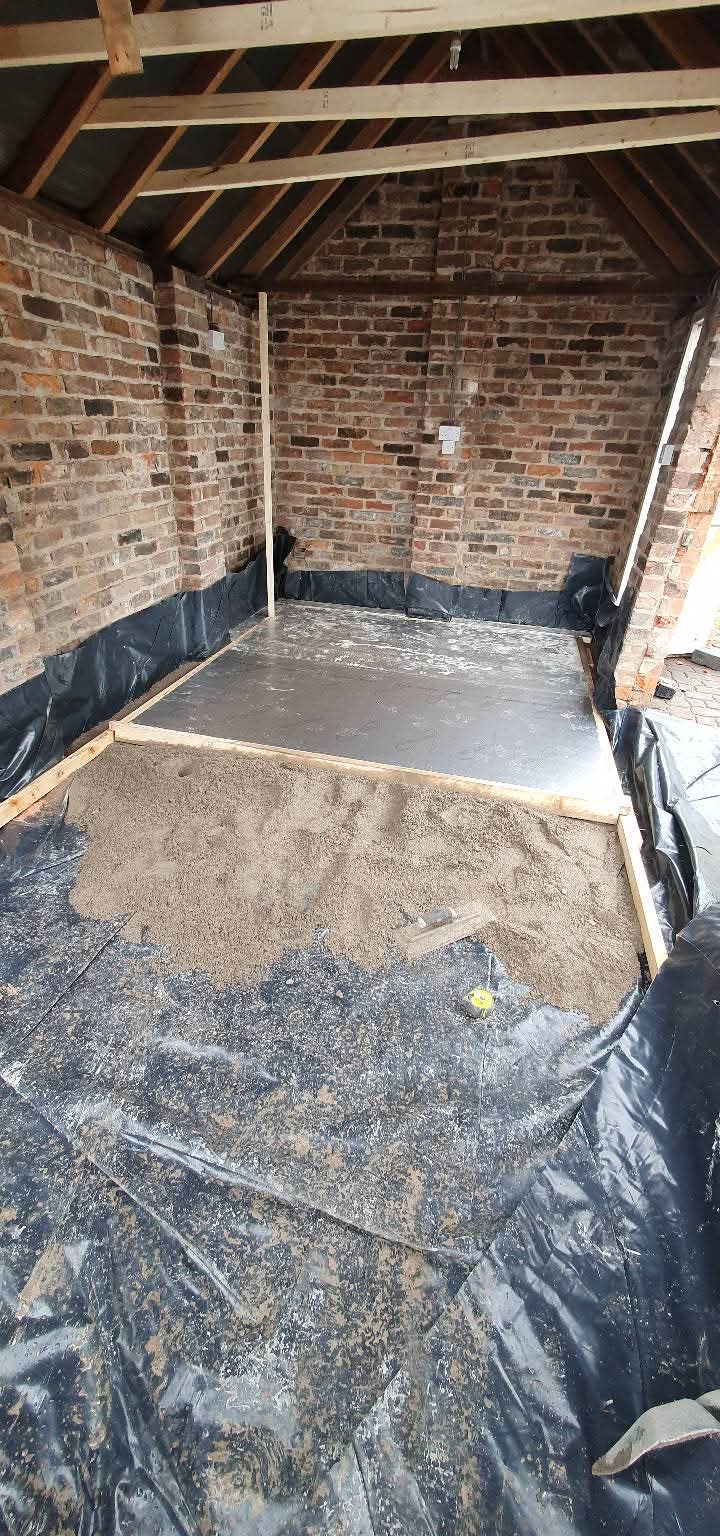 Garage interior with exposed roof timbers and floor preparation