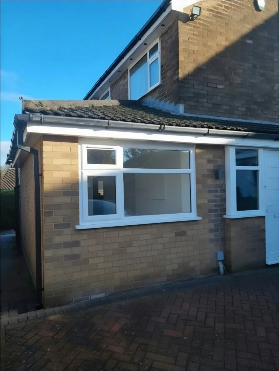 Exterior of the Marple garage conversion, with brickwork and a white window where the garage door once stood