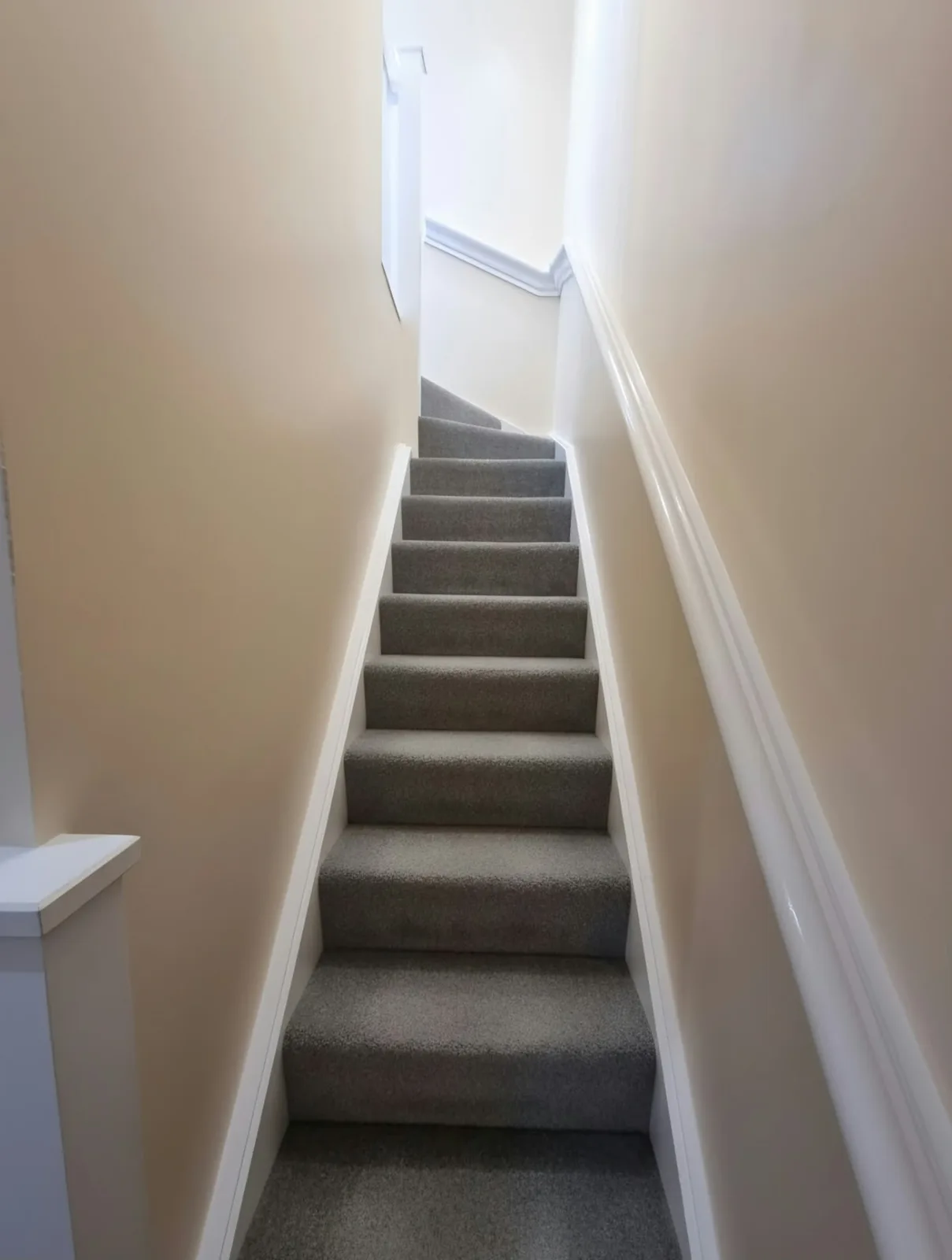 Finished carpeted staircase leading up to the Prestwich loft conversion with a wall-mounted handrail