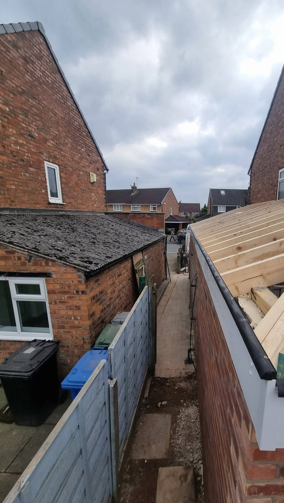 Side extension brick wall with exposed roof rafters, white fascia and black gutter