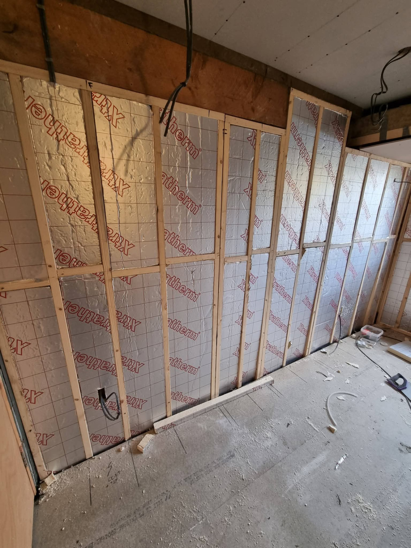 Foil-faced wall insulation between timber battens with exposed electrical cables