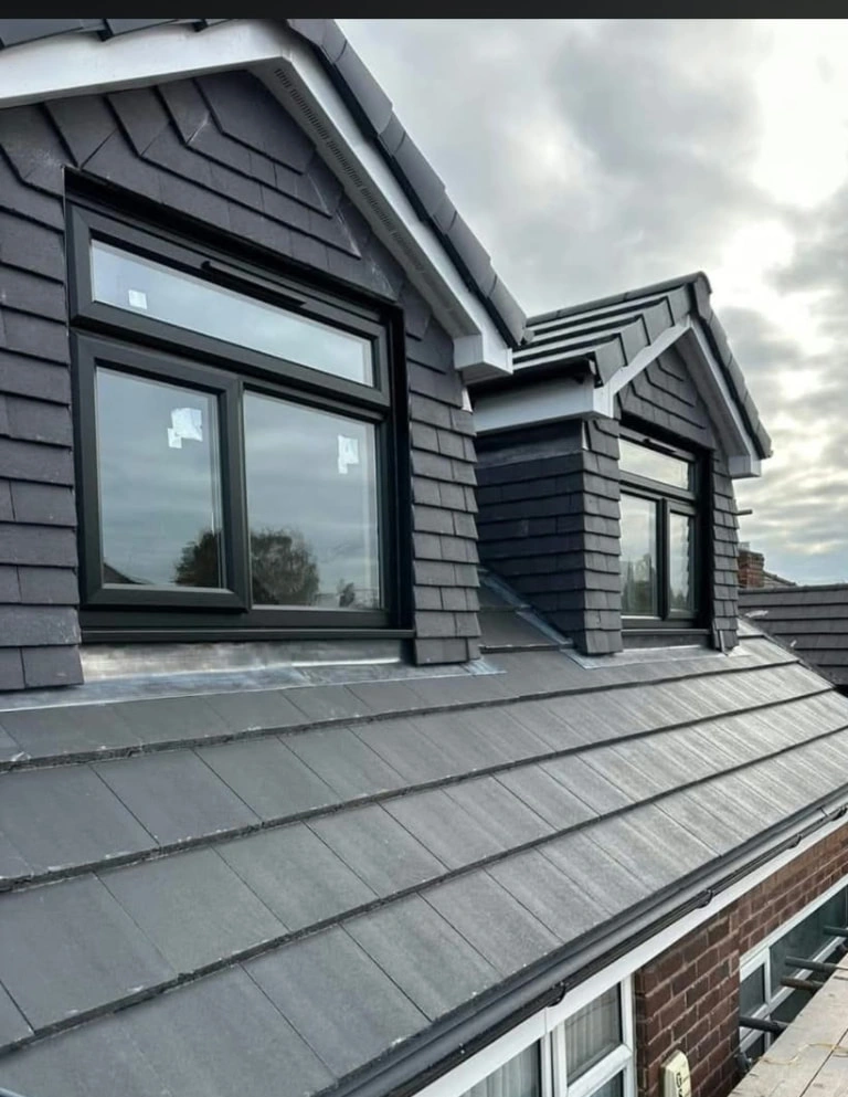 Close exterior view of the Prestwich dormers, dark roof finishes and roofline, with scaffolding still in place