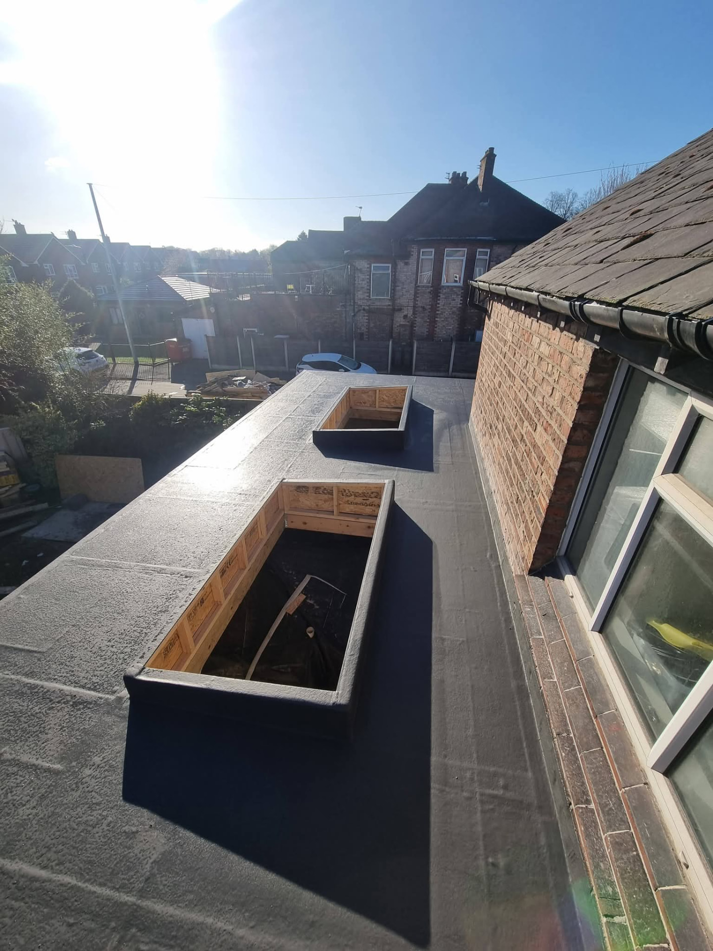 Flat roof covering with two raised timber rooflight openings