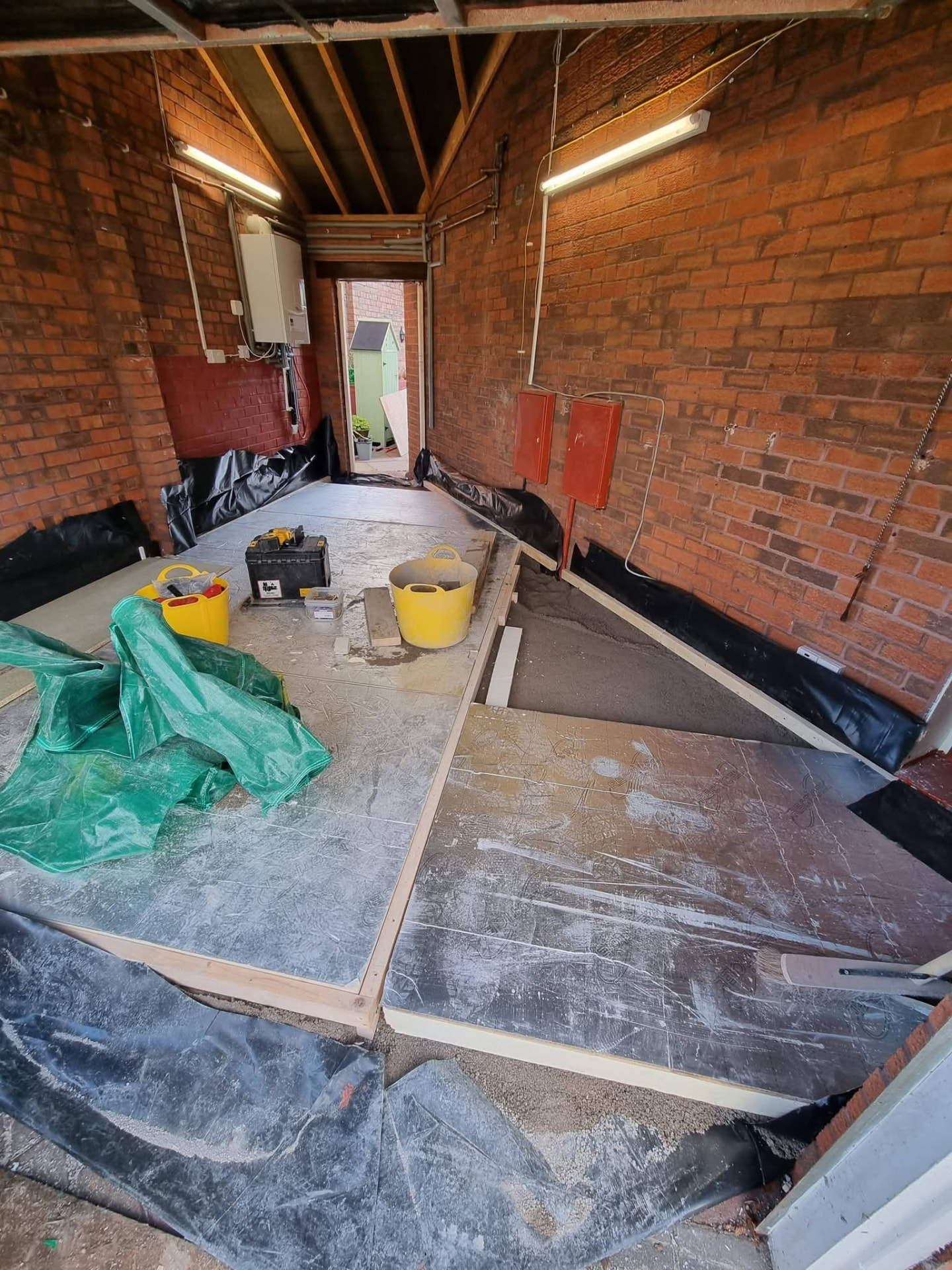 Garage interior during floor preparation with brick walls, insulation and timber edging