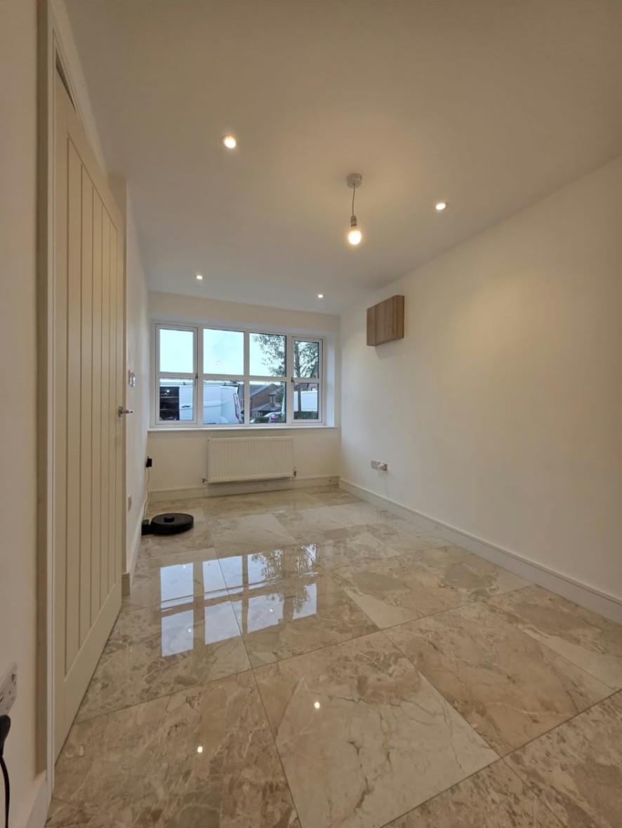 Bright converted room with polished tiled floor, radiator and front window